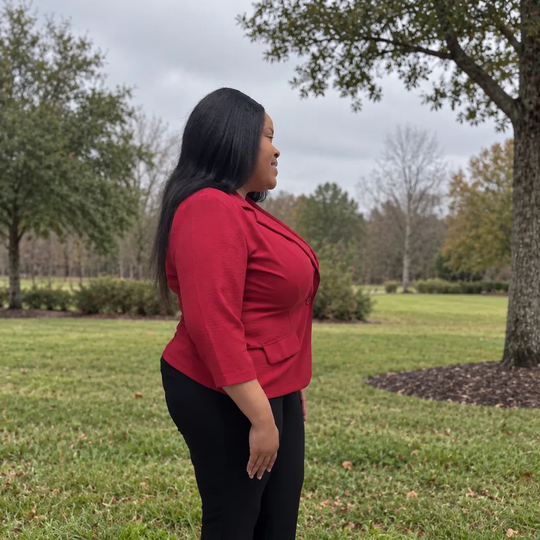 Natacha standing quietly outdoors among trees