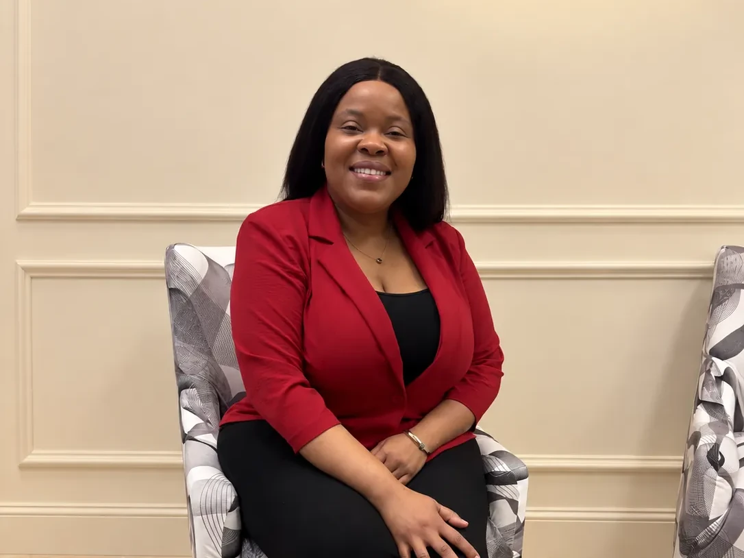 Natacha Alcindor seated, smiling, in a red blazer