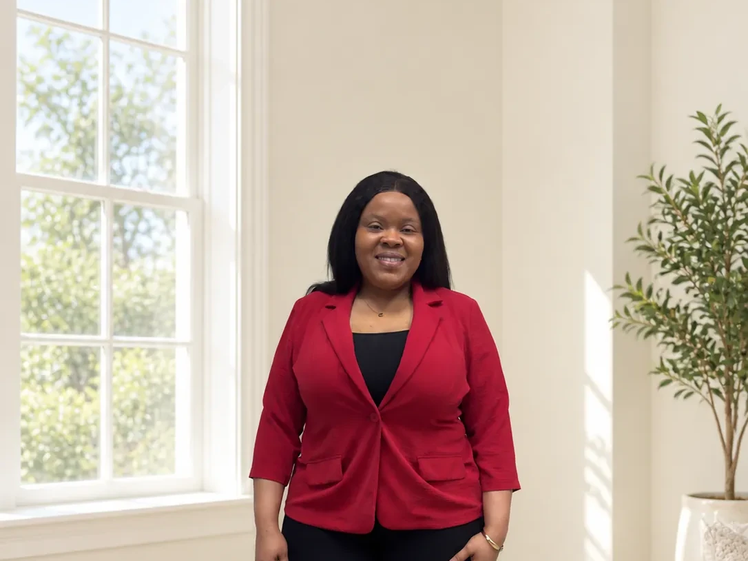 Natacha Alcindor standing, smiling, in a red blazer